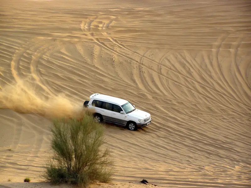 SUV driving across golden sand dunes on a Dubai desert safari
