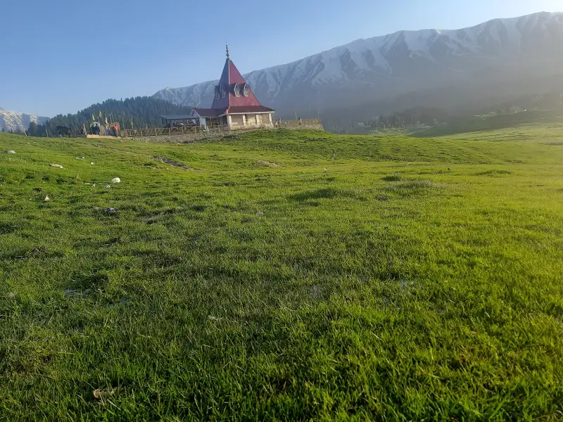 Green meadow and hilltop temple in Gulmarg, Kashmir