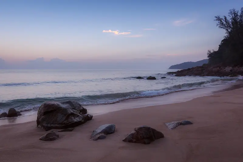 Quiet beach with rocks at sunset in Phuket, Thailand