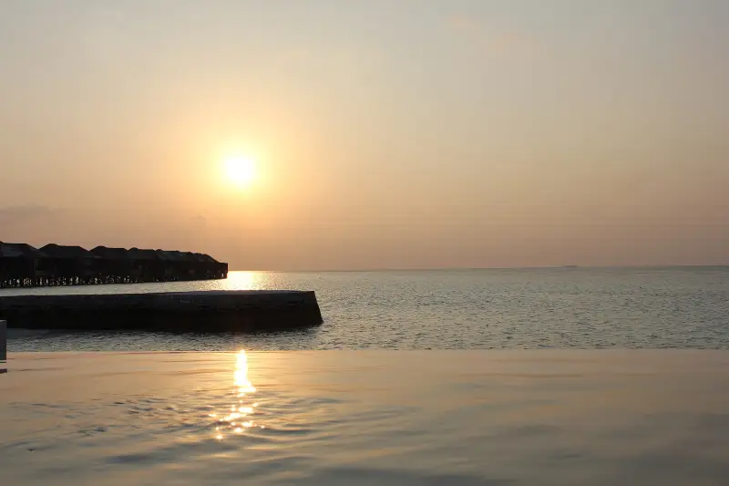 Couple swimming at sunset in the calm sea of the Maldives